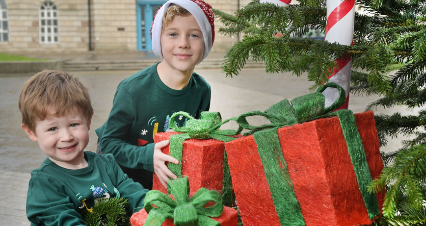 Two children pose with parcel props beside Newtownards Christmas Tree in Conway Square